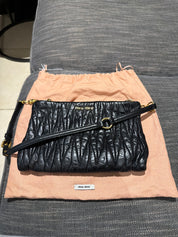 Miu Miu black leather clutch with long strap.