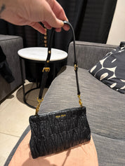 Miu Miu black leather clutch with long strap.