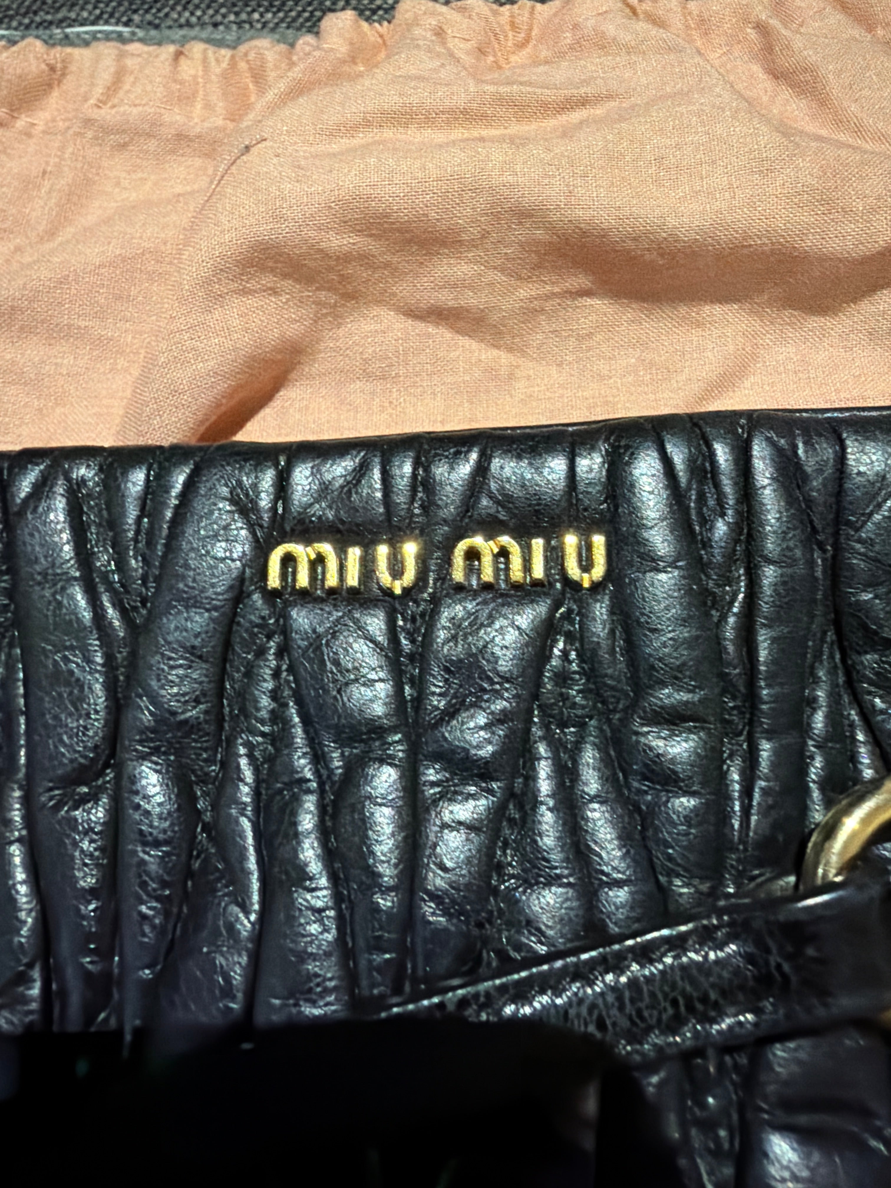 Miu Miu black leather clutch with long strap.